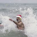 크리스마스 복장의 수영인들이 쌀쌀한 아침에 축제 수영을 위해 물속으로 이미지